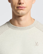 The Psycho Bunny MENS ARCHIE MELANGE COLOR BLOCK SWEATSHIRT - B6S630F200, crafted from soft cotton jersey, features an embroidered bunny with crossed golf clubs on the chest. A neutral backdrop enhances its monochrome style and subtle details.
