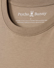 Close-up of the Psycho Bunny men's classic crew neck tee in beige, featuring the iconic bunny with crossbones logo. Made from 100% Pima cotton, the label highlights this premium piece crafted in Peru. Product: MENS CLASSIC CREW NECK TEE - B6U014CRPC.