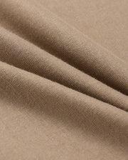A close-up of beige fabric with a smooth texture shows soft folds and gentle shadows. Resembling the lightweight, finely woven 100% Pima cotton in the MENS CLASSIC CREW NECK TEE - B6U014CRPC by Psycho Bunny, it highlights its delicate and even surface.