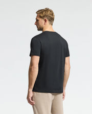 A man with short blond hair, facing away, wears a Psycho Bunny MENS CLASSIC CREW NECK TEE - B6U014CRPC made of 100% Pima cotton and beige pants against a plain white background.