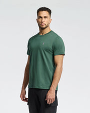 A man with short curly hair wears the Psycho Bunny MENS CLASSIC CREW NECK TEE (B6U014F200) in green, featuring a small embroidered chest logo, paired with black pants against a plain light background.