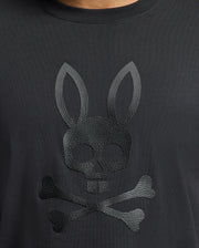 The Men's Payson Leather Print Graphic Tee from Psycho Bunny is crafted from soft Pima cotton jersey and features an embossed skull with bunny ears above crossed bones, echoing the classic pirate motif.