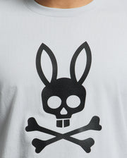 A close-up of the Psycho Bunny MENS PAYSON LEATHER PRINT GRAPHIC TEE - B6U213E200 features a gray Pima cotton jersey shirt with a black skull with rabbit ears, and two crossed bones in a playful pirate design highlighted by detailed leather print.