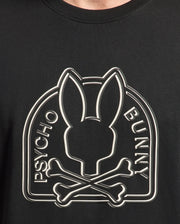 Close-up of the black MENS MELBOURNE GRAPHIC TEE - B6U410F200 by Psycho Bunny, made eco-friendly, featuring the iconic Bunny graphic with a rabbit head silhouette above crossed bones and "Psycho" and "Bunny" vertically on each side.