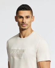 A man with short dark hair and trimmed facial hair wears the Psycho Bunny MENS SYDNEY WORDMARK GRAPHIC TEE (B6U510F200), featuring "PSYCHO BUNNY" on the front, standing against a plain light background and looking at the camera.
