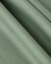 Close-up of a soft, light green fabric with visible ridges and folds. Made in Peru, the Pima cotton of the MENS MALTON GRAPHIC TEE - B6U795D200 from Psycho Bunny appears smooth and slightly textured, suggesting a comfortable and gentle material.