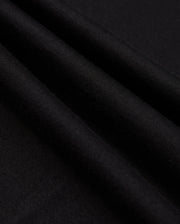 Close-up of the neatly folded black Pima cotton fabric with a soft texture. Three prominent folds create shadows, emphasizing the smooth material. The image highlights the quality and richness of Psycho Bunny's MENS JAMES PREMIUM CREW NECK TEE - B6U952D200, showcasing its sleek and elegant appearance.
