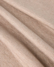 Close-up image of soft, light brown fabric with visible texture. The fabric appears to be folded in several smooth, gentle creases, showcasing its flexibility and softness. Made from premium Pima cotton, the material looks like it could be perfect for the MENS JAMES PREMIUM CREW NECK TEE - B6U952D200 by Psycho Bunny.