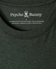 A close-up of the inside label of a dark green MENS JAMES PREMIUM CREW NECK TEE - B6U952D200, featuring the brand name "Psycho Bunny" along with a rabbit logo. The text indicates that the stylish crew neck shirt is made from 100% premium Pima cotton and was made in Peru.