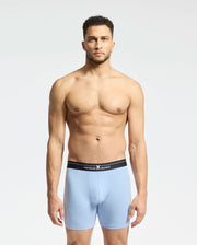 A shirtless man models light blue Psycho Bunny MENS 2 PACK BOXER BRIEF - B6V481F200, made from a soft Modal blend with a black waistband featuring sleek text and a small emblem on an understated white or light gray background.