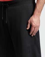 A person showcases Psycho Bunny’s MENS BIG AND TALL LEVANZO EMBROIDERED MICRO FRENCH TERRY SWEATSHORT (B9R578F200) in black, featuring a drawstring and embroidered bunny logo near the pocket. Made from soft micro French Terry for comfort.