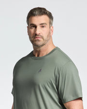 A bearded man with short brown hair wears the Psycho Bunny BIG AND TALL CLASSIC CREW NECK TEE - B9U014CRPC in green, made from 100% Pima cotton, featuring a small chest embroidery. He faces the camera against a light backdrop.
