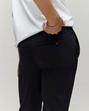 A child models the Psycho Bunny KIDS WADE CORD PATCH SWEATPANT (KB0800002), posing with a hand in the back pocket to showcase the classic athletic waist and hip design.