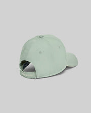 The KIDS DEREK BASEBALL CAP (KO1500008) by Psycho Bunny is shown from the back in light green, crafted from premium cotton with an adjustable strap and bold white "Psycho Bunny" embroidery, set against a plain gray background.