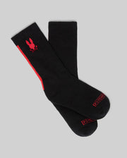 A set of Psycho Bunny KIDS 3 PACK SPORT SOCKS (KO2200005) features black cotton socks with red accents, including a bunny skull logo and "PSYCHO" in red on the toes, photographed against a gray background.