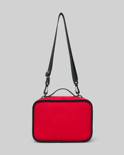 The PSYCHO BUNNY LUNCH BOX - KO2400002 by Psycho Bunny is a rectangular red insulated lunch box featuring black edges, a top black handle, and an adjustable shoulder strap, shown against a plain gray background.