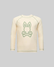 The Psycho Bunny KIDS LONG SLEEVE RASHGUARD - KT0200027 is cream-colored with a large light green Bunny head and crossed bones on the front, shown against a plain gray background.