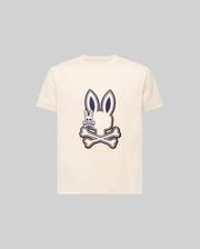 The KIDS WADE GRAPHIC TEE - KT0200054 by Psycho Bunny is a cream-colored 100% cotton tee with a large bunny head and crossbones graphic, plus a small smiling embroidered Bunny on the chest. The background is light gray.