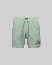 The Psycho Bunny MENS ELIAS SWIM TRUNK - MB1000008 features light green textured fabric, a classic fit, drawstring waistband, and darker green "Beach Bliss" embroidery on the lower left leg. Shown on a plain light gray background.