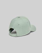 The Psycho Bunny MENS DEREK BASEBALL CAP - MO1500009 in light green, crafted from bold cotton, is shown from the back with an adjustable strap and "Psycho Bunny" embroidery, set against a plain gray background.