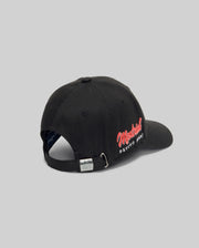 A rear view of the Psycho Bunny MENS MONTREAL BASEBALL CAP (MO1500048), black and 100% cotton, with an adjustable metal-clip strap and red and white "Montreal PSYCHO PRINT" embroidery on the side. Light gray background.