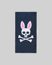 The Psycho Bunny MENS MICROFIBER TOWEL - MO1700007 is dark blue, featuring a white skull with pink-eared bunny ears above crossed bones, set against a plain gray background.