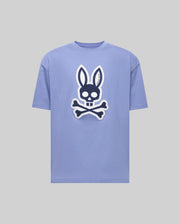 The Psycho Bunny MENS RYDER OVERSIZED FIT TEE (MT0200062) is a light purple premium tee with a bold black and white bunny skull and crossbones graphic on the front, shown against a plain gray background.