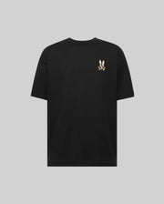 The Psycho Bunny MENS WADE OVERSIZED FIT CHEST TEE (MT0200152) is a plain black Pima cotton shirt with a relaxed fit, featuring a small embroidered cartoon bunny with crossed bones on the upper left chest.