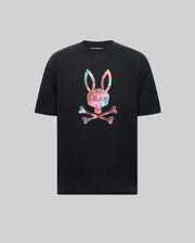 The Psycho Bunny MENS NOVAN GRAPHIC TEE - MT0200177 is a black Pima cotton shirt featuring a vibrant tie-dye style Printed Bunny with upright ears above crossed bones on the chest, set against a gray background.