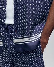 A person wears the Psycho Bunny MENS HUNTER TENCEL SHIRT - MT0300016, a navy blue breathable set with a white bunny logo pattern and “PSYCHO BUNNY” text near the hem; their hand is in their pocket.