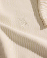 A close-up of the Psycho Bunny MENS MARIO STRIPED SWEATER T-SHIRT (MT0400009) in cream shows ribbed knit fabric with an embroidered bunny head on the chest and a partially visible sleeve highlighting the striped texture.