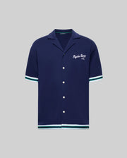 The Psycho Bunny MENS BASIL TAPED CAMP COLLAR SHIRT - MT0500004 is a navy short-sleeve cotton-modal shirt with white/green striped trim, Johnny collar, white buttons, and "Psychic Bunny 2022" embroidered on the chest.