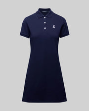 The Psycho Bunny WOMENS POLO DRESS - WO2000003 is a navy blue short-sleeve Pima polo dress with a collar, four white buttons, and a small white Bunny logo on the left chest, shown on a plain gray background.