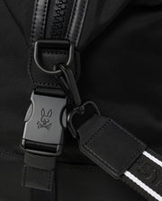Close-up of the versatile Psycho Bunny MENS WEEKENDER BAG - B6A629Z1BG in black fabric, featuring a metal clip and buckle with a signature skull and bunny ears logo. Black leather strap with white stitching attaches to the buckle, highlighting the zipper and fabric texture.