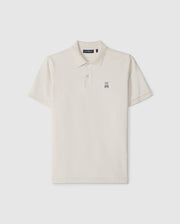 The Psycho Bunny Men's Classic Pique Polo Shirt (B6K001B200) in beige features a two-button placket, short sleeves, and an embroidered rabbit logo on the left chest. Made from soft Pima cotton, it epitomizes men's fashion essentials against a plain white background.