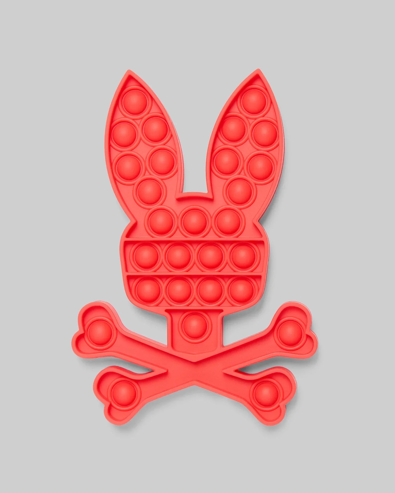 The Psycho Bunny PSYCHO BUNNY POP IT - B0A376E200 is a red silicone pop-it toy shaped like a bunny's head above crossed bones, blending stress relief with playful, skull-and-crossbones-inspired design.
