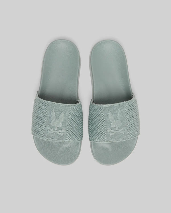 Psycho Bunny KIDS KNIT SLIDES - B0A377F200 in light green feature knit textile, textured straps with a bunny and crossbones logo, and an ergonomically molded footbed, displayed against a plain light background.