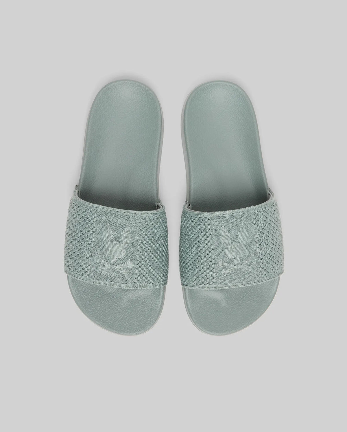 Psycho Bunny KIDS KNIT SLIDES - B0A377F200 in light green feature knit textile, textured straps with a bunny and crossbones logo, and an ergonomically molded footbed, displayed against a plain light background.