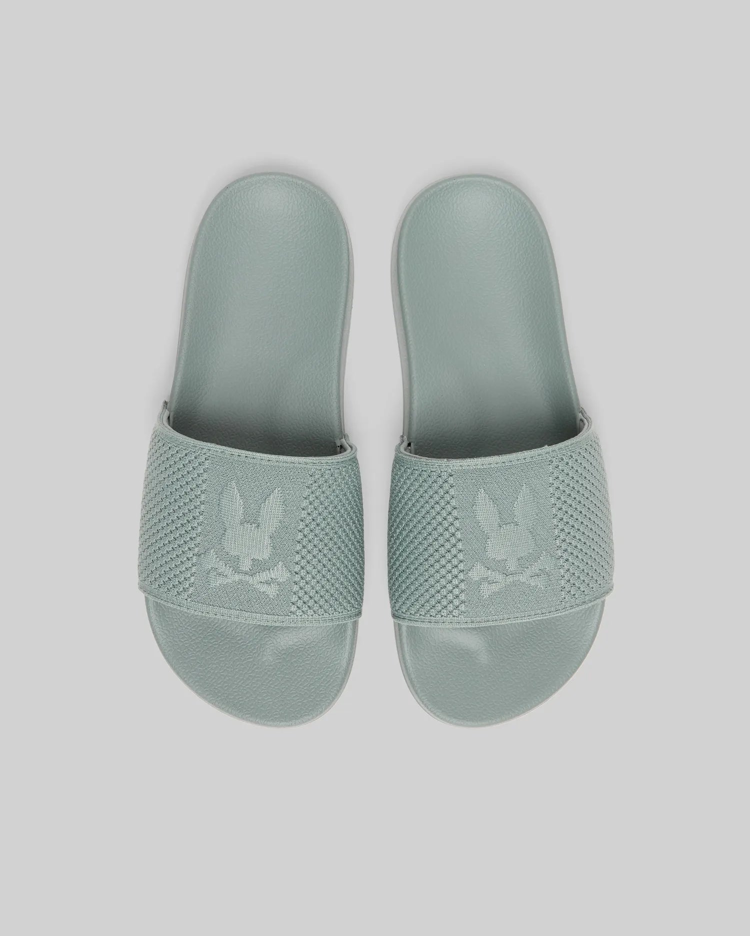 Psycho Bunny KIDS KNIT SLIDES - B0A377F200 in light green feature knit textile, textured straps with a bunny and crossbones logo, and an ergonomically molded footbed, displayed against a plain light background.