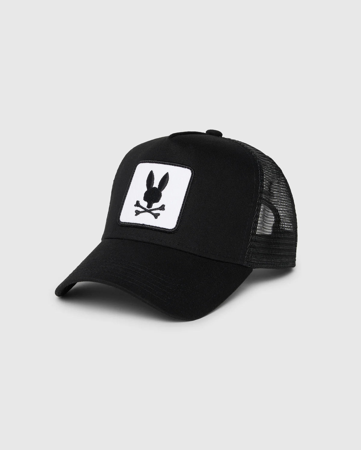 The Psycho Bunny KIDS BUNNY PATCH TRUCKER CAP (B0A965C200) features breathable mesh panels and a front patch with a white bunny logo, including a black bunny head and crossbones.