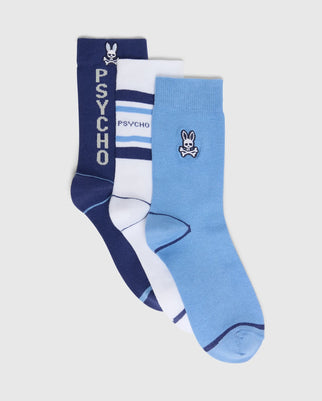 The Psycho Bunny KIDS 3 PACK FASHION DRESS SOCK B0F504F200 includes a dark blue pair with "PSYCHO" text, a white pair with blue stripes and "PSYCHO" text, and a light blue pair. Made from premium Pima cotton, each pair features embroidered Bunny logos and playful skull designs.