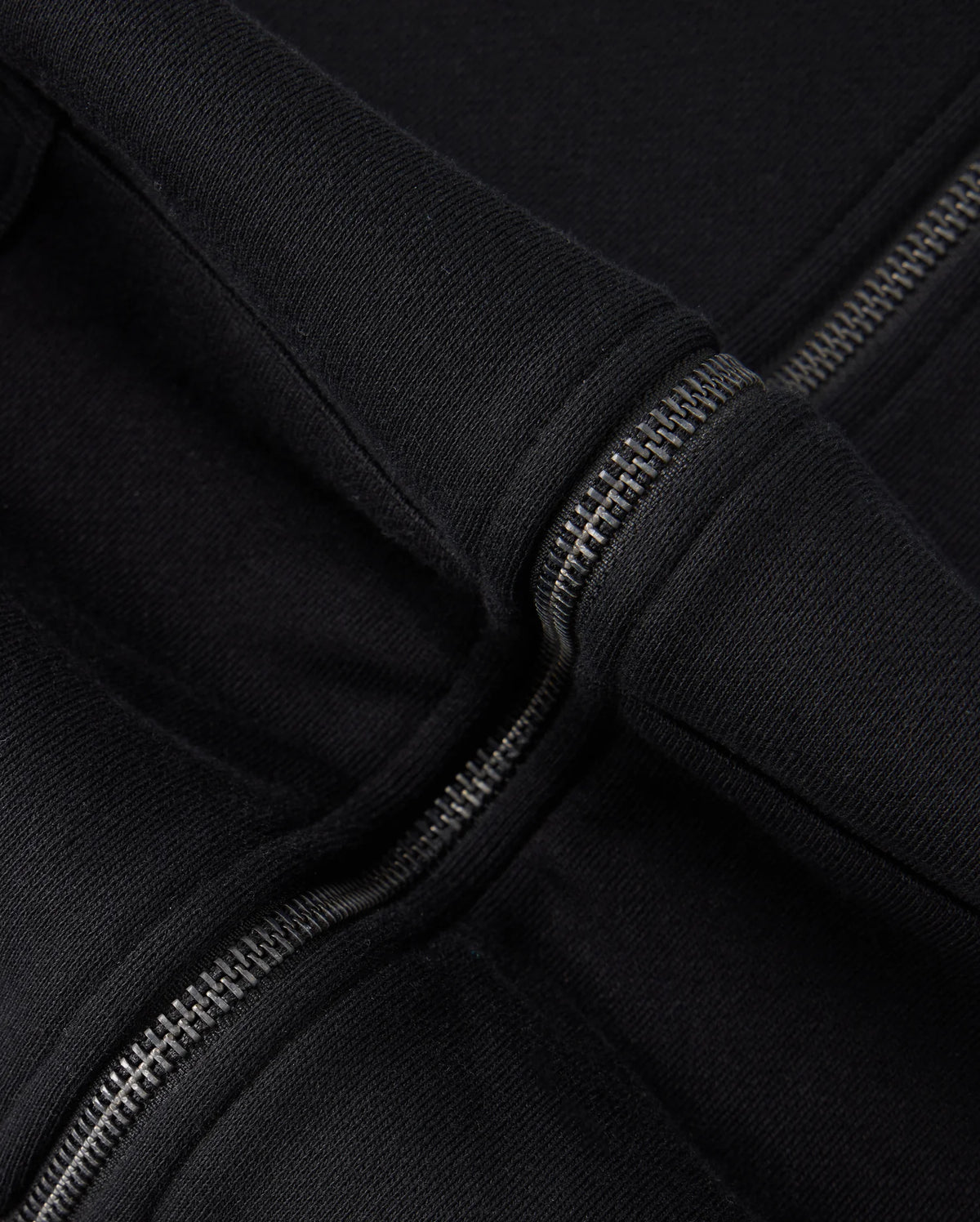 Close-up image of the Psycho Bunny KIDS LEVY ZIP FLEECE HOODIE - B0H720D200 in black, highlighting the metal zipper and the seam where the hood attaches to the main body of the garment. The thick, fleece-lined fabric appears soft and warm, ideal for little ones.