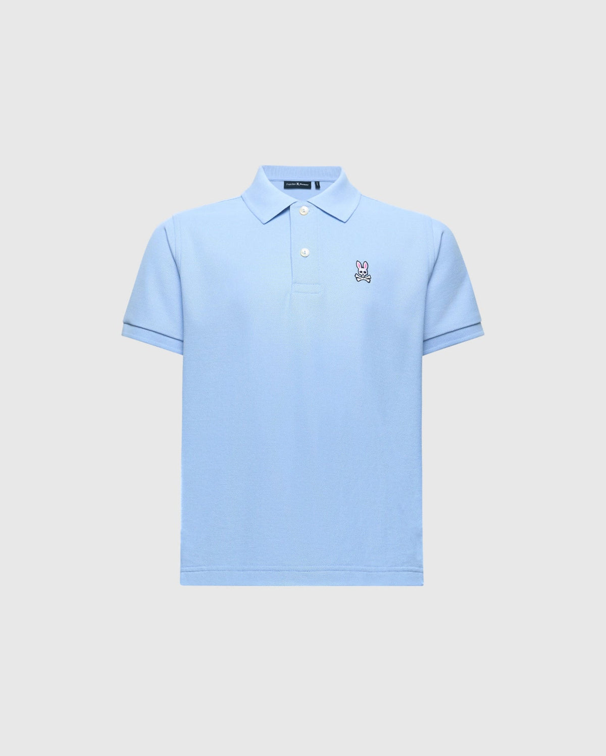 The Psycho Bunny KIDS CLASSIC PIQUE POLO (B0K001B200) is a light blue shirt with short sleeves, a folded collar, and button-up neckline. Made from Pima cotton, it features an embroidered bunny logo on the left chest against a plain gray background.