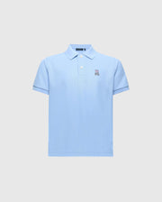 The Psycho Bunny KIDS CLASSIC PIQUE POLO (B0K001B200) is a light blue shirt with short sleeves, a folded collar, and button-up neckline. Made from Pima cotton, it features an embroidered bunny logo on the left chest against a plain gray background.