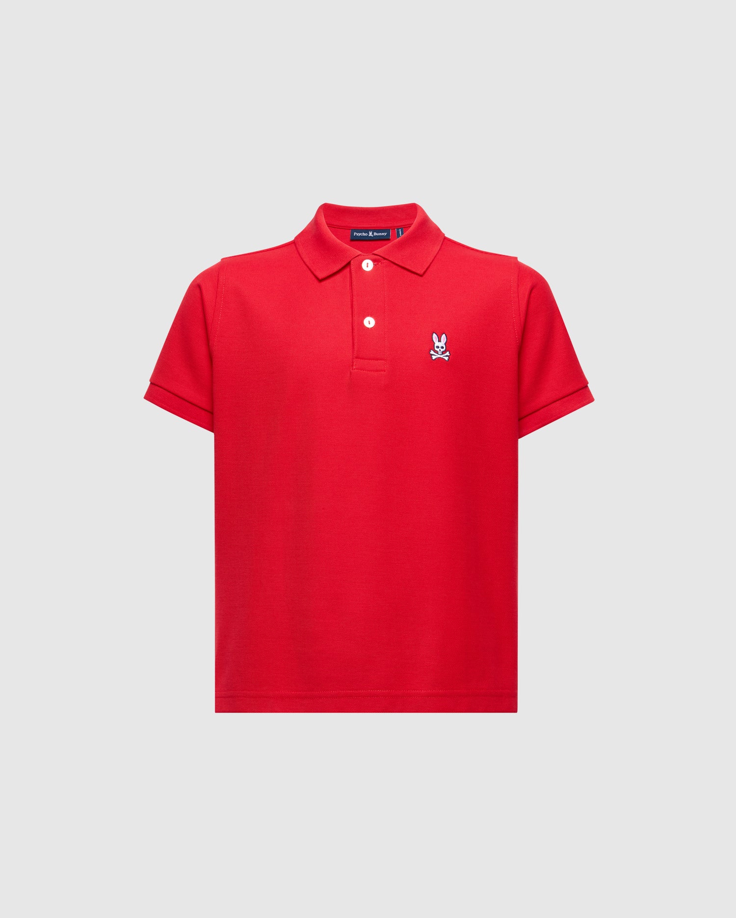The KIDS CLASSIC PIQUE POLO SHIRT - B0K001CRPC by Psycho Bunny is a bright red Pima cotton polo for kids, with a collar, three buttons, and an embroidered white Psycho Bunny logo on the left chest, shown against a plain light background.
