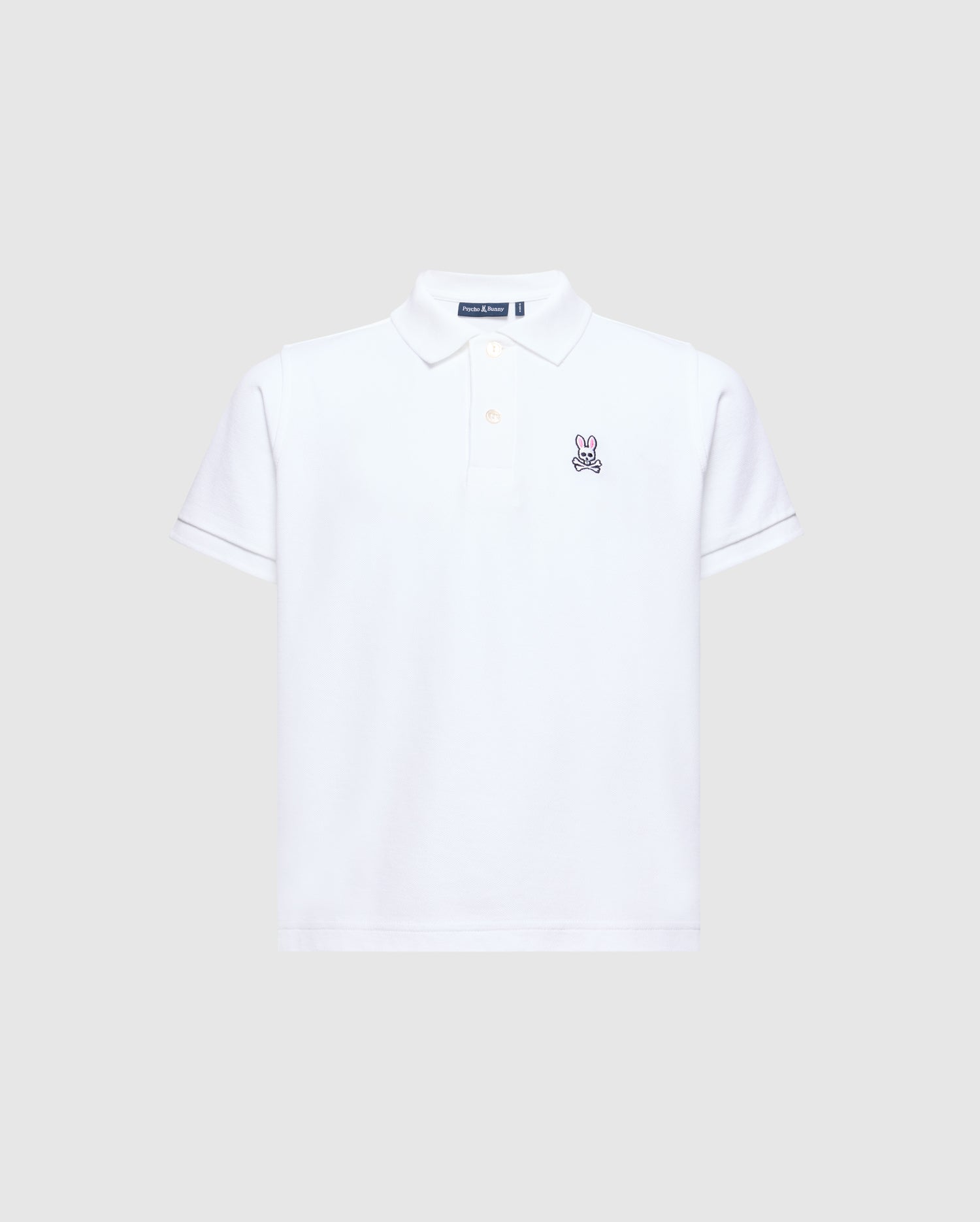 The Psycho Bunny Kids Classic Pique Polo Shirt (B0K001CRPC) is a white short-sleeved polo shirt made from soft Pima cotton. It features an embroidered rabbit logo on the left chest and has a classic collar with a button-up placket, all set against a light grey background.