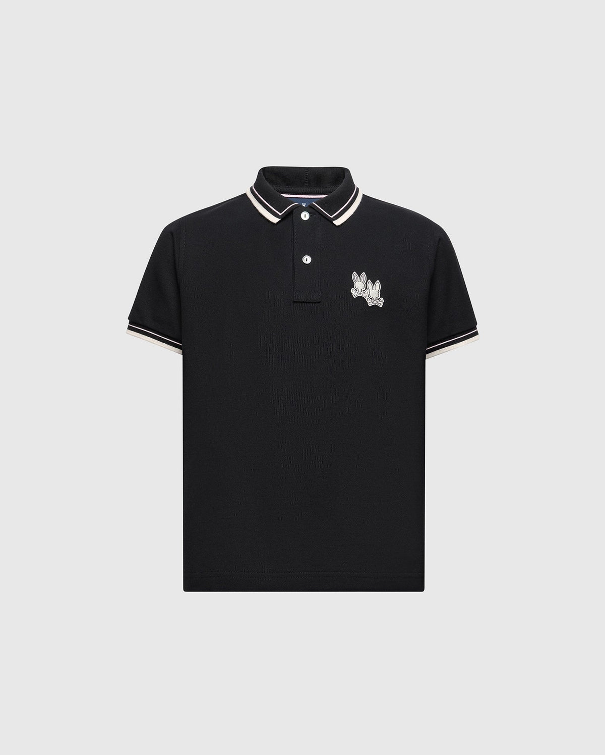 The KIDS ELLIOT PIQUE POLO - B0K505F200 by Psycho Bunny is a black polo made from soft Pima cotton, highlighted with white and tan trim on the collar and sleeves, featuring a playful embroidered Bunny on the left chest, elegantly displayed against a light gray background.