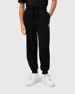A person wearing Psycho Bunny's KIDS LEVY ESSENTIAL FLEECE SWEATPANT (B0P721D200) in black and white sneakers stands against a plain background.