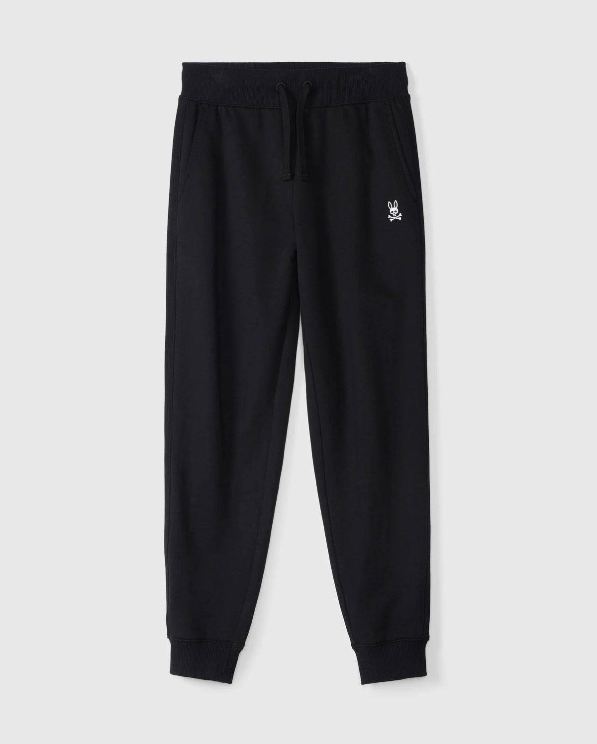 The Psycho Bunny KIDS LEVY ESSENTIAL FLEECE SWEATPANT in black, product B0P721D200, offers ultimate comfort with its elastic waistband, drawstring, and cuffed ankles. Featuring a small white embroidered logo on the upper left side, they are shown on a plain gray background to highlight the cozy fabric.