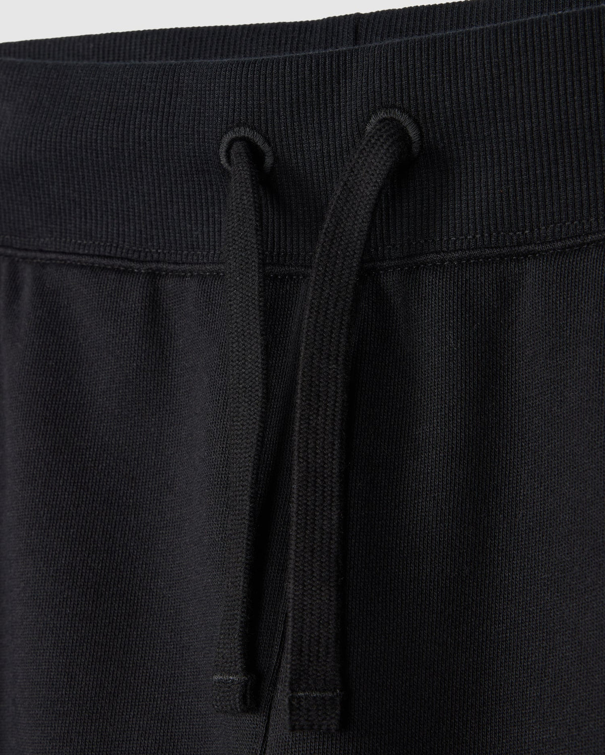The Psycho Bunny KIDS LEVY ESSENTIAL FLEECE SWEATPANT (B0P721D200) showcases black cotton with a ribbed waistband and black drawstrings. The cozy fleece fabric is soft and slightly textured, ideal for casual wear.